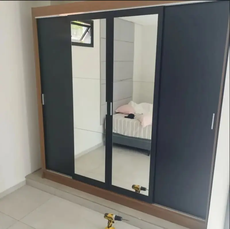 Guarda-roupa de correr preto com espelho, montado em quarto